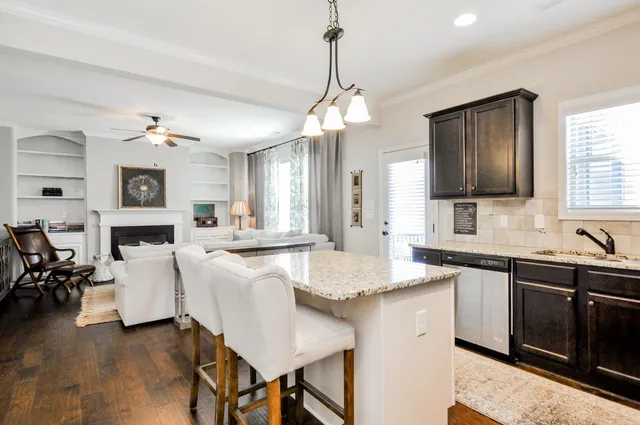 a kitchen with cabinets a sink dishwasher a dining table and chairs with wooden floor