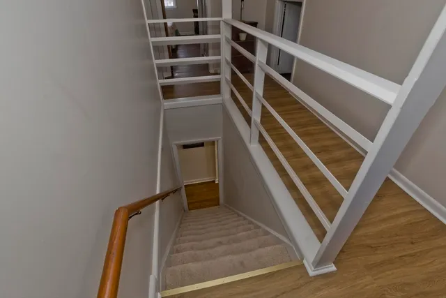 a view of an empty room with wooden floor and stairs