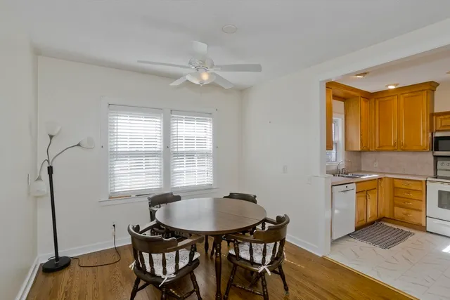 a kitchen with stainless steel appliances granite countertop a stove a sink dishwasher a dining table and chairs with wooden floor