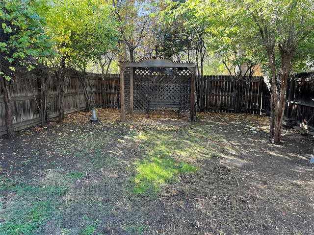 a backyard of a house with large trees and wooden fence