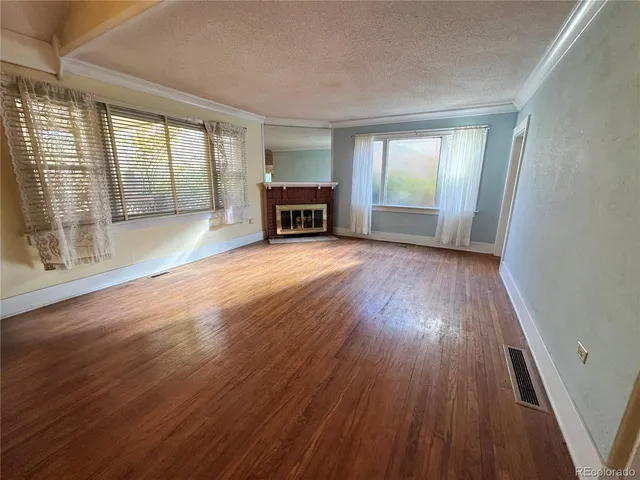 an empty room with wooden floor and large windows