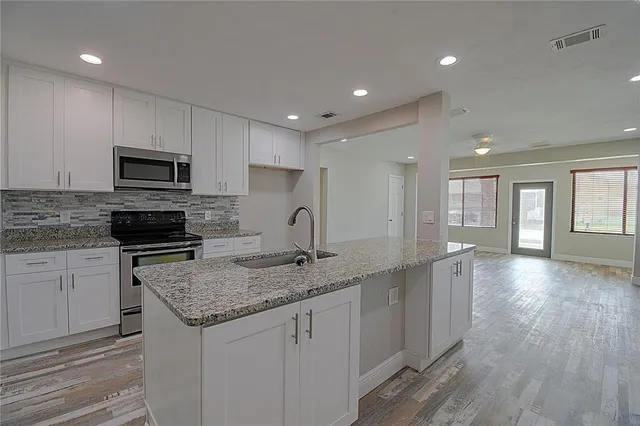 a kitchen with granite countertop kitchen island sink stove and cabinets
