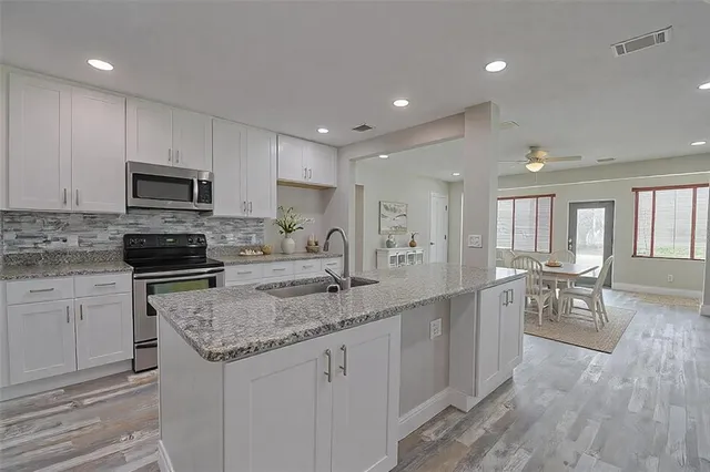 a kitchen with granite countertop a stove top oven a sink a counter space and cabinets