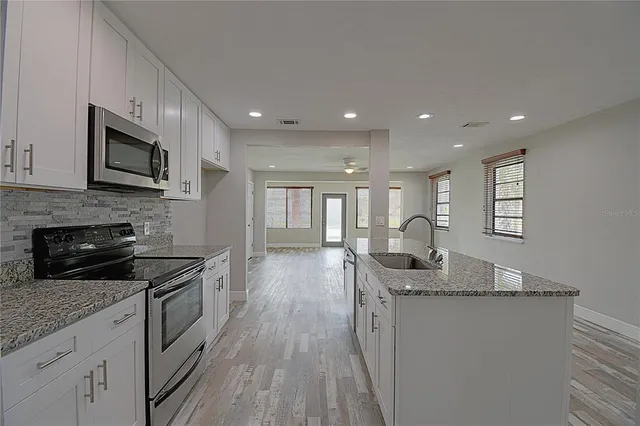 a kitchen with granite countertop kitchen island stainless steel appliances a stove sink microwave and cabinets
