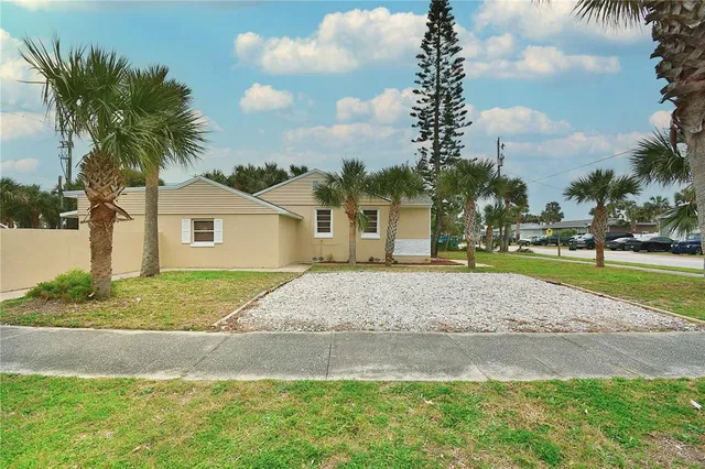 a view of a house with a yard and palm trees