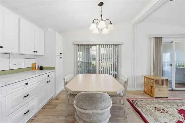 a living room with stainless steel appliances granite countertop a sink a stove a dining table and chairs