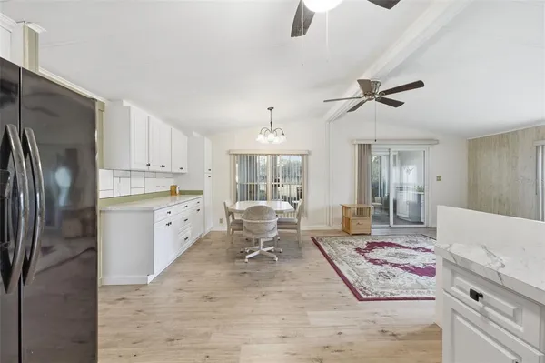 a living room with stainless steel appliances furniture a rug and a chandelier