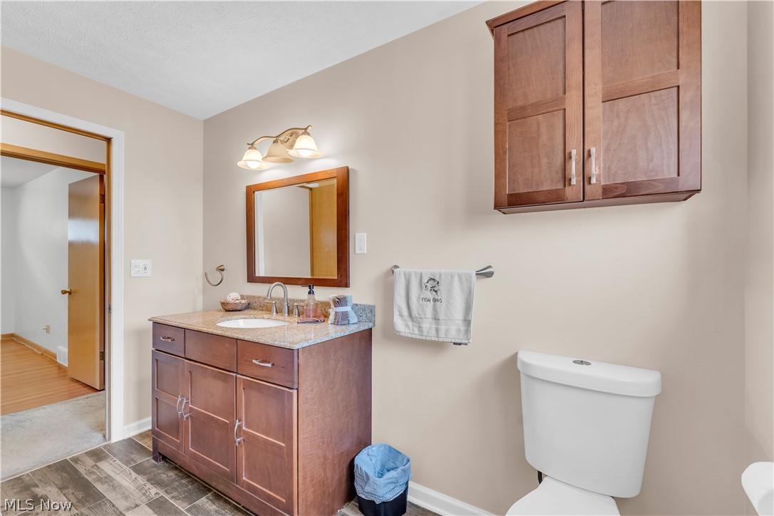 3023 Norris Avenue Cleveland, OH 44134 - Photo 27 of 41 Bathroom featuring a wood-finish vanity with granite countertop, undermount sink, and wall-mounted mirror