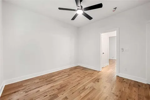 an empty room with wooden floor and a ceiling fan