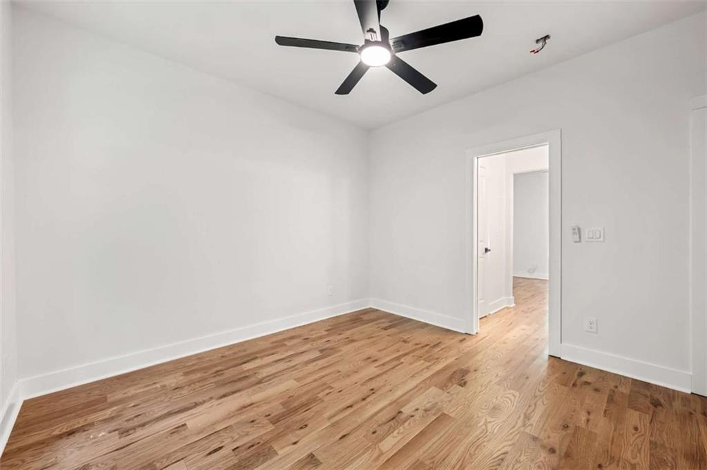 1606 Blvd Lorraine Southwest Atlanta, GA 30311 - Photo 19 of 24 an empty room with wooden floor and a ceiling fan