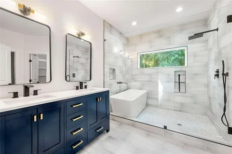 a bathroom with a tub a sink shower and mirror