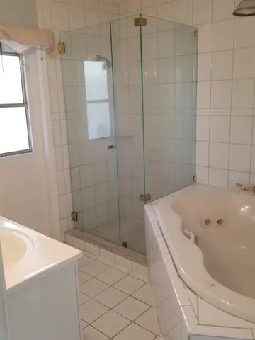 a bathroom with a white bath tub a shower and a sink