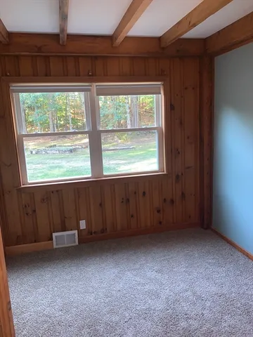 a view of an empty room with closet and a mirror