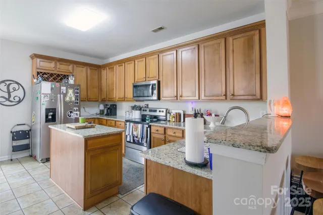 a kitchen with stainless steel appliances granite countertop a stove top oven a sink dishwasher and a refrigerator with wooden cabinets