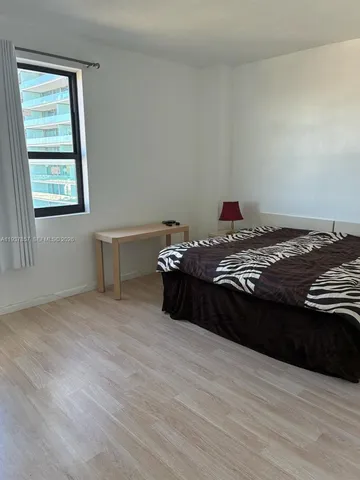 a room with a bed and a potted plant on the dresser