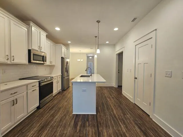 a large kitchen with cabinets wooden floor and stainless steel appliances
