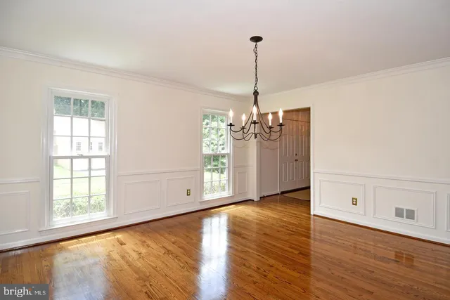an empty room with wooden floor fireplace and windows