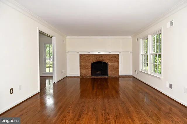 an empty room with wooden floor a fireplace and windows