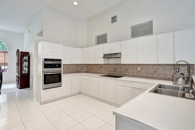 a kitchen with granite countertop a refrigerator and a stove top oven