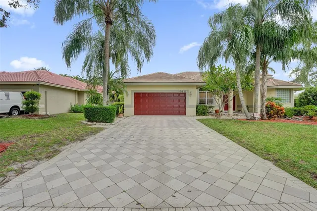 front view of a house with a yard and palm trees