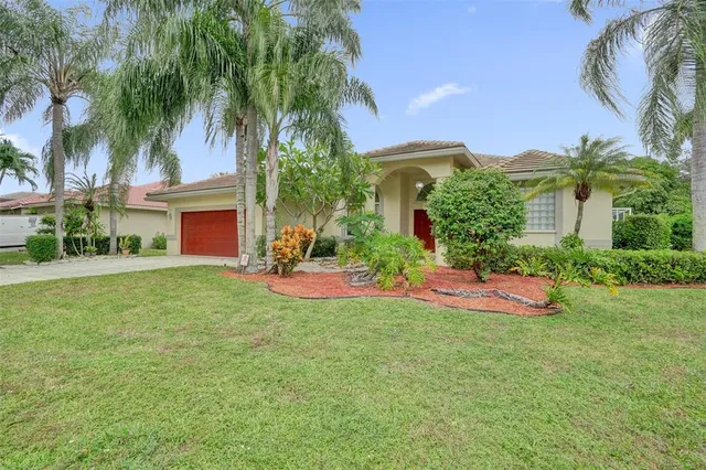 front view of a house with a yard and palm trees