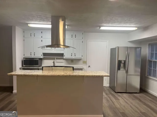 a large kitchen with stainless steel appliances a sink a stove a refrigerator and cabinets