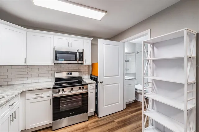 a kitchen with cabinets stainless steel appliances and wooden floor