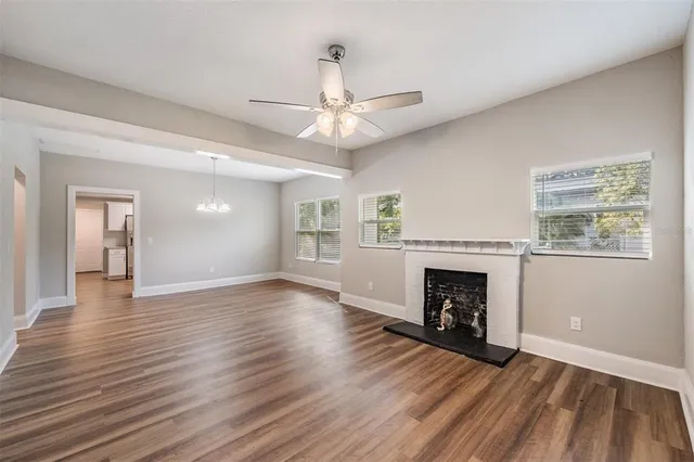 an empty room with wooden floor fireplace and windows