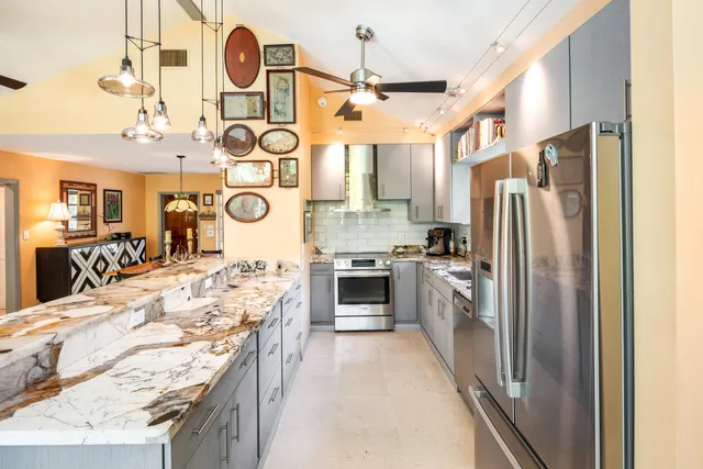 a kitchen with stainless steel appliances granite countertop a refrigerator a stove and a sink