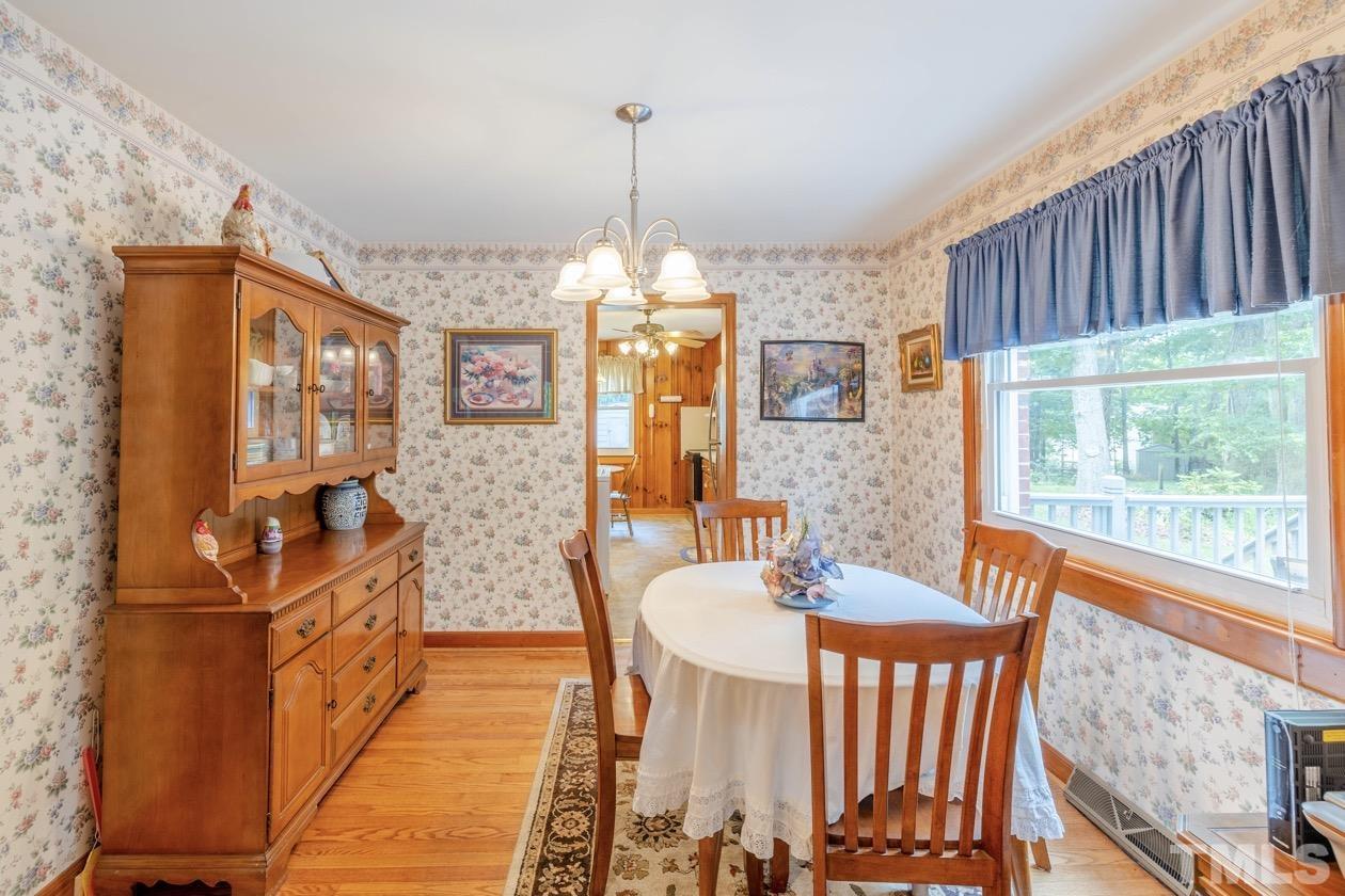 2804 Sparger Road Durham, NC 27705 - Photo 21 of 34 a dining room with wooden floor a chandelier a wooden table and chairs