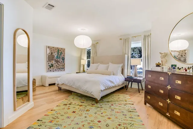 a bedroom with a bed and dresser with mirror