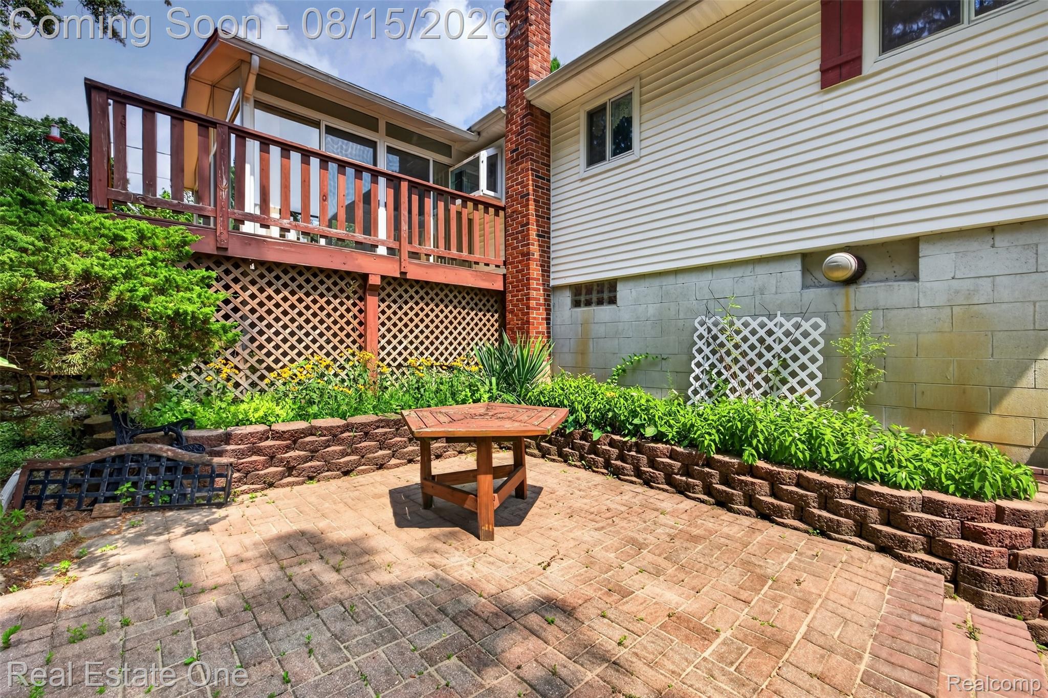 454 South Baldwin Road Oxford, MI 48371 - Photo 41 of 64 Brick paver patio with tiered retaining walls, a raised deck with wood railing, and mature landscaping