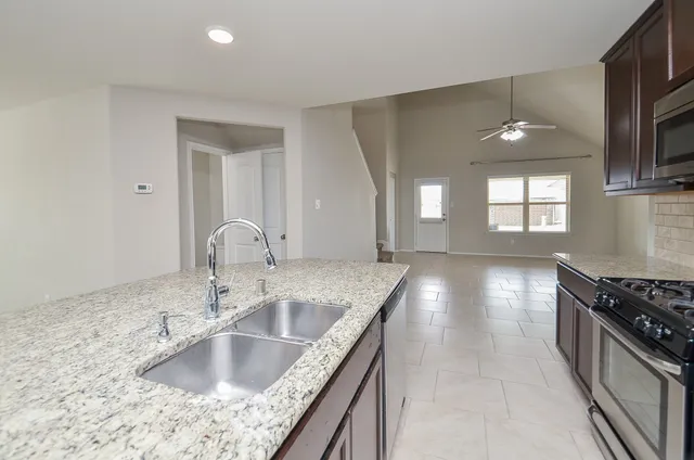 a kitchen with stainless steel appliances granite countertop a sink a stove and a wooden floors