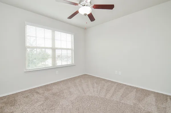 an empty room with a window and a fan