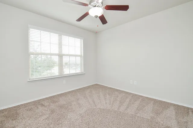 an empty room with a window and a fan