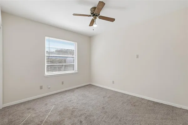 an empty room with a window and a ceiling fan