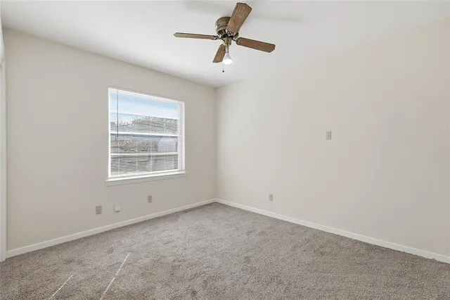 an empty room with a window and a ceiling fan