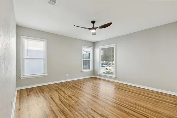 a view of an empty room with wooden floor and a window