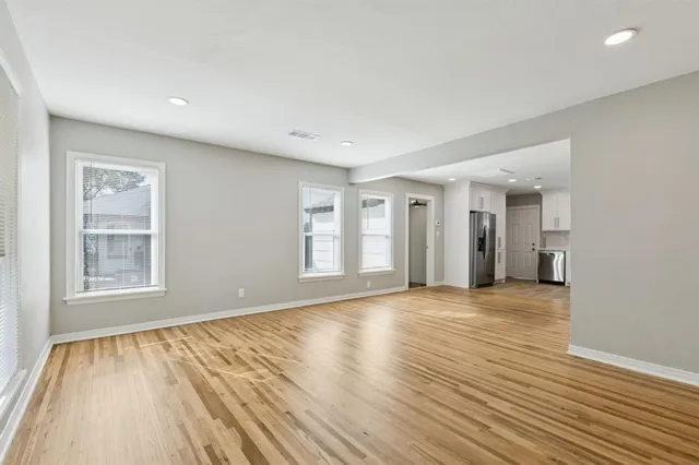 a view of an empty room with wooden floor and a window