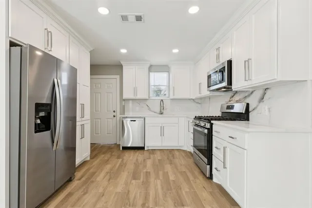a kitchen with white cabinets and stainless steel appliances