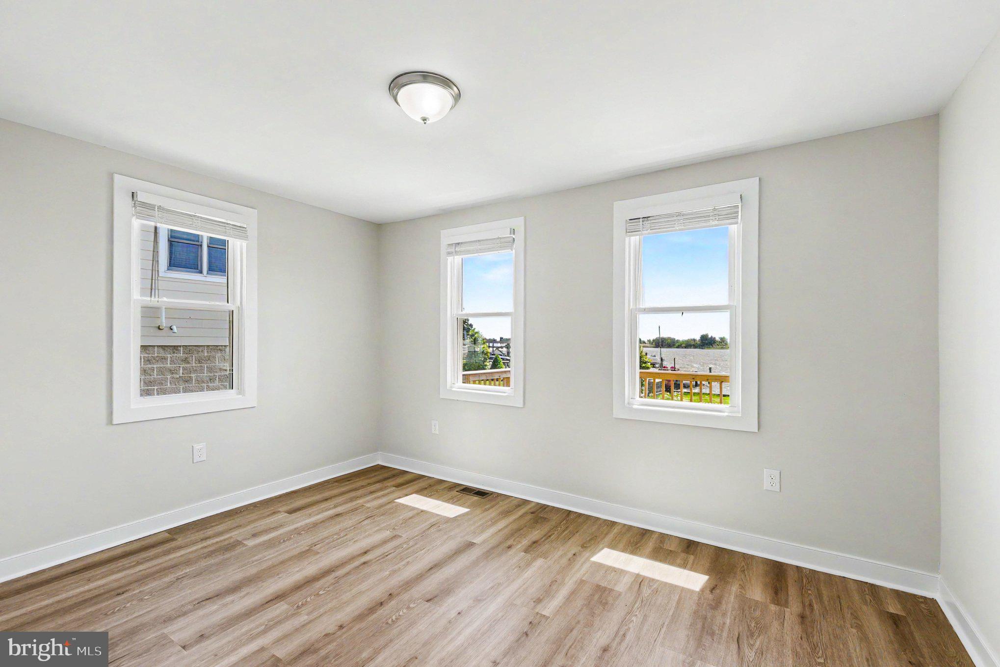 9135 Cuckold Point Road Sparrows Point, MD 21219 - Photo 14 of 44 a view of an empty room with wooden floor and a window