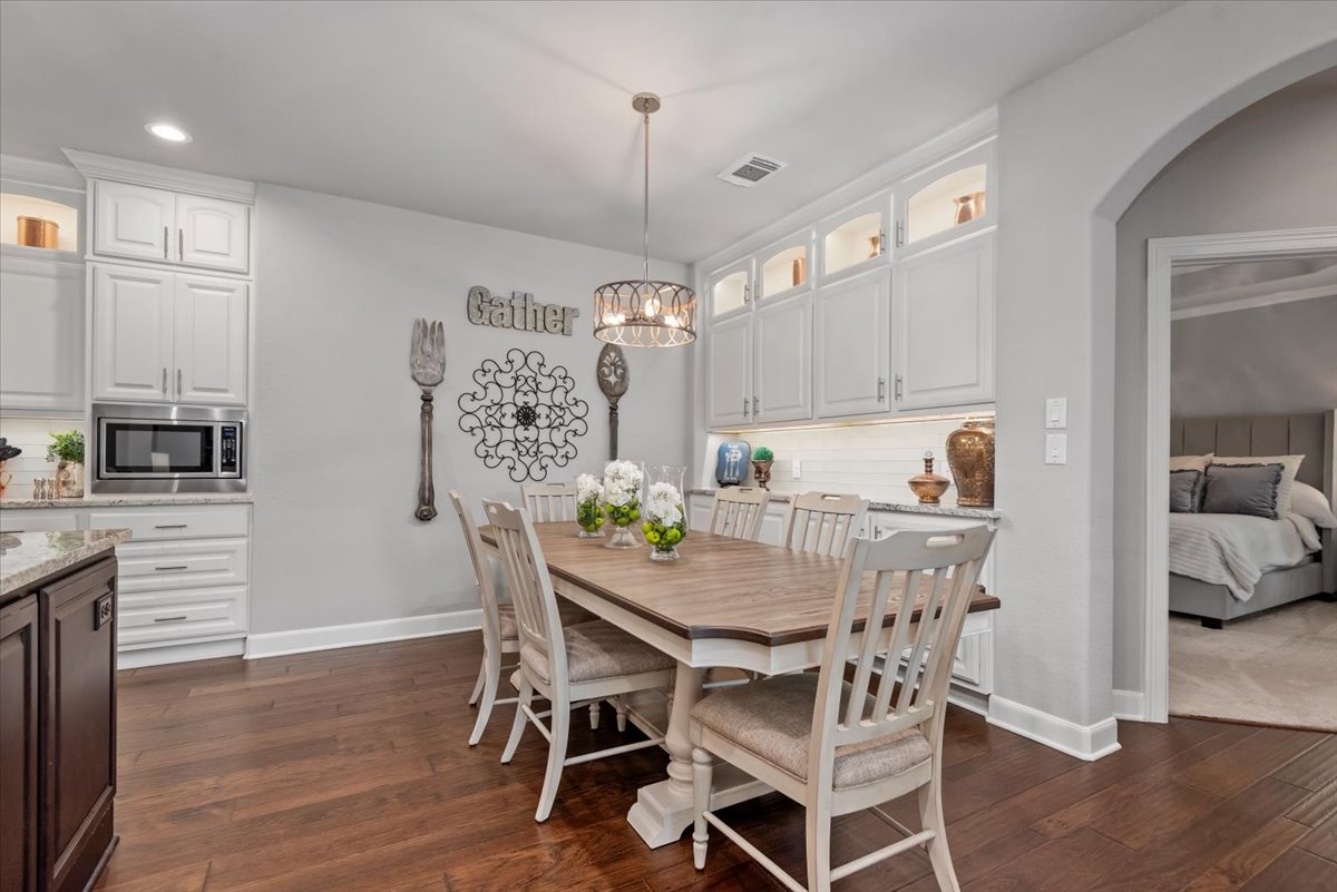 15519 Stallion Point Circle Cypress, TX 77429 - Photo 14 of 37 Dining area featuring hardwood floors, a chandelier, and white cabinetry with under-cabinet lighting