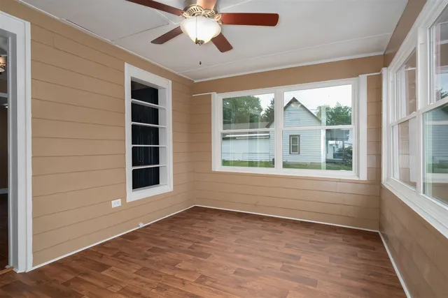 a view of an empty room with a window and wooden floor