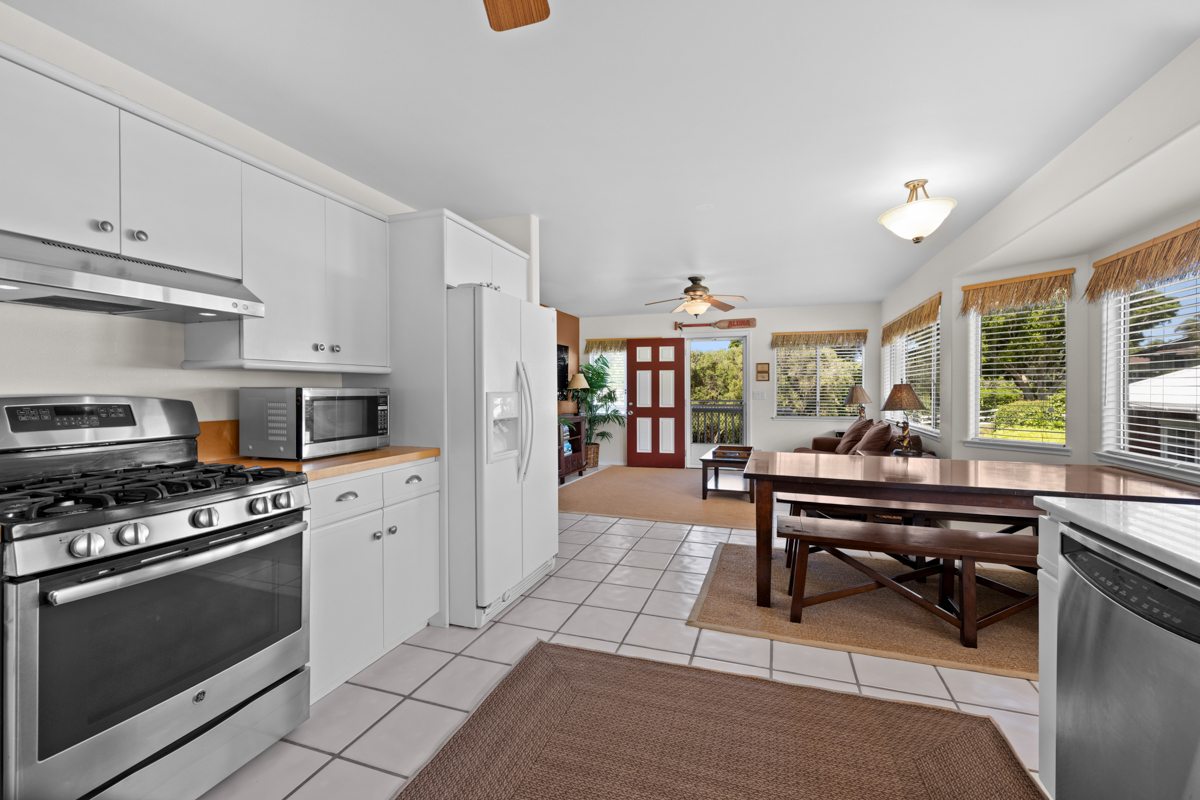 66-1685 Kohala Mountain Road Kamuela, HI 96743 - Photo 6 of 26 a kitchen with stainless steel appliances kitchen island granite countertop a stove a sink dishwasher and white cabinets with wooden floor