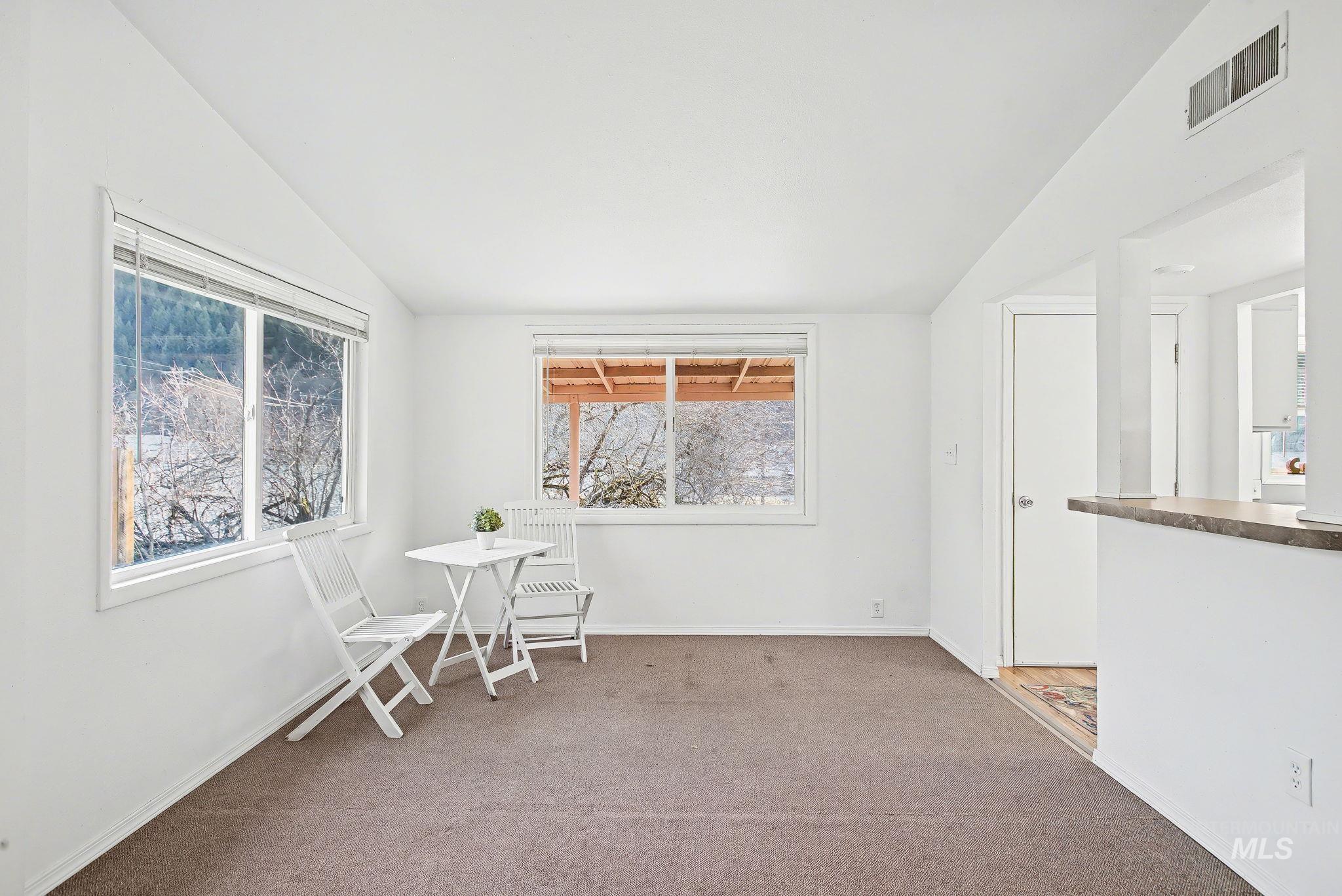 150 Elm Street Orofino, ID 83544 - Photo 8 of 36 Bright living area featuring twin windows, neutral carpeting, white painted walls, and a pass-through opening with a countertop