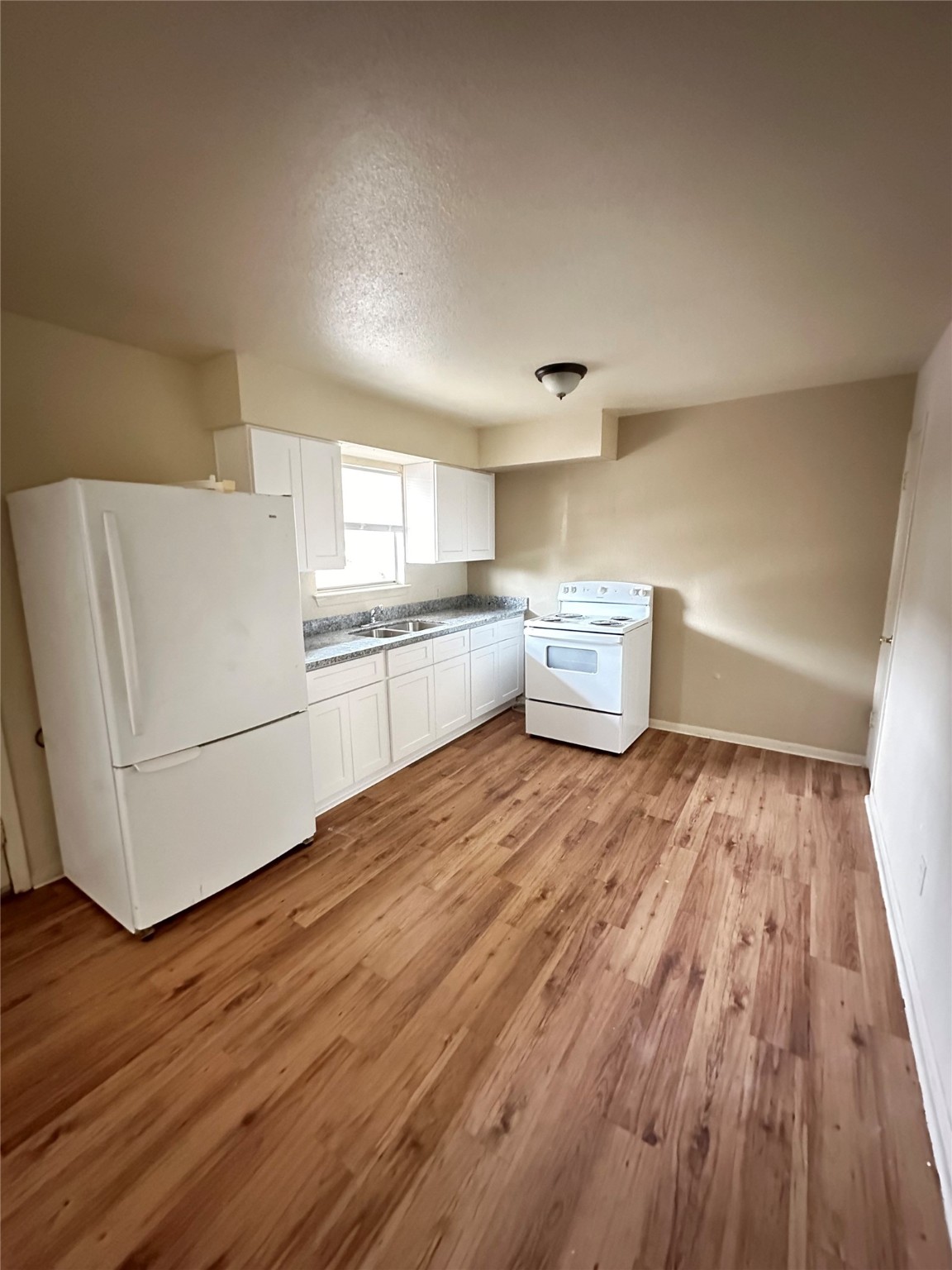 201 Sands Street, Unit 19 Angleton, TX 77515 - Photo 3 of 6 a kitchen with a wooden floor and white appliances