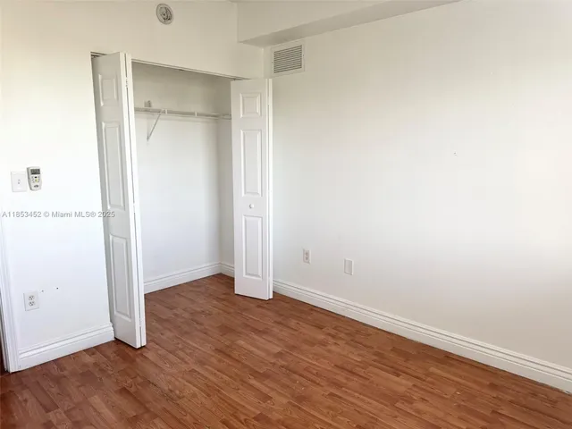 an empty room with wooden floor & closet