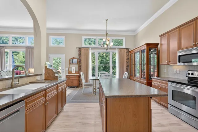 a large kitchen with stainless steel appliances a large counter top a stove a chimney a sink and a large window