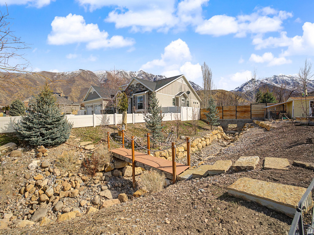 968 South Cyn Road Santaquin, UT 84655 - Photo 28 of 36 Backyard featuring a decorative wooden bridge over a dry creek bed, stone retaining walls, and mature evergreen trees