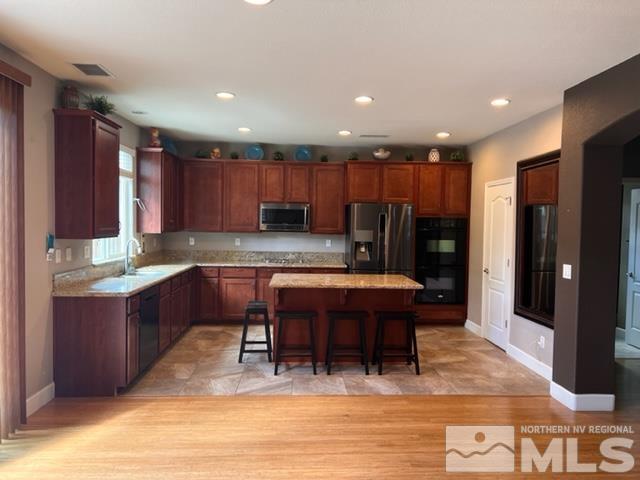 a kitchen with kitchen island granite countertop wooden cabinets a refrigerator a sink and a stove